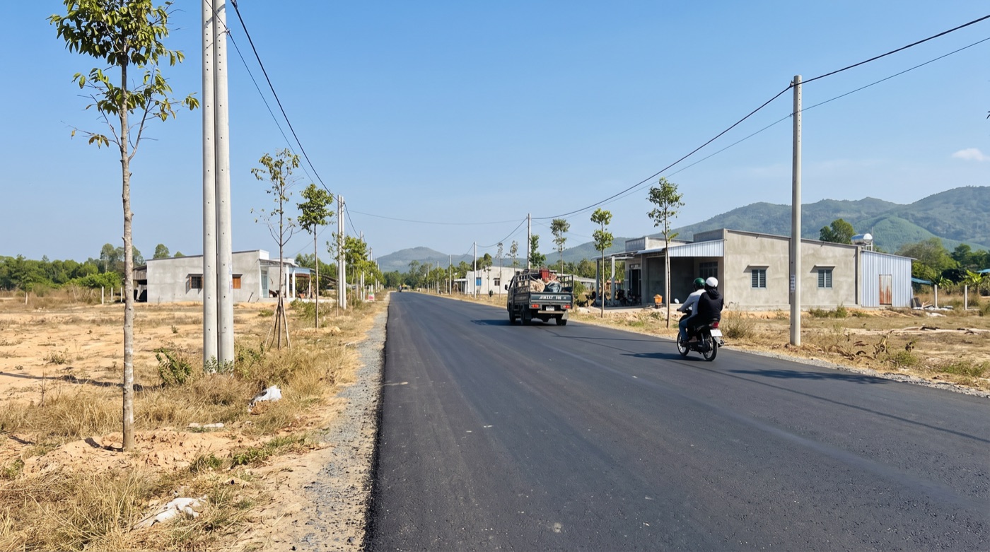 Đường nhựa mới chạy qua khu đất nền, hai bên có nhà dân — hạ tầng kết nối quyết định giá đất